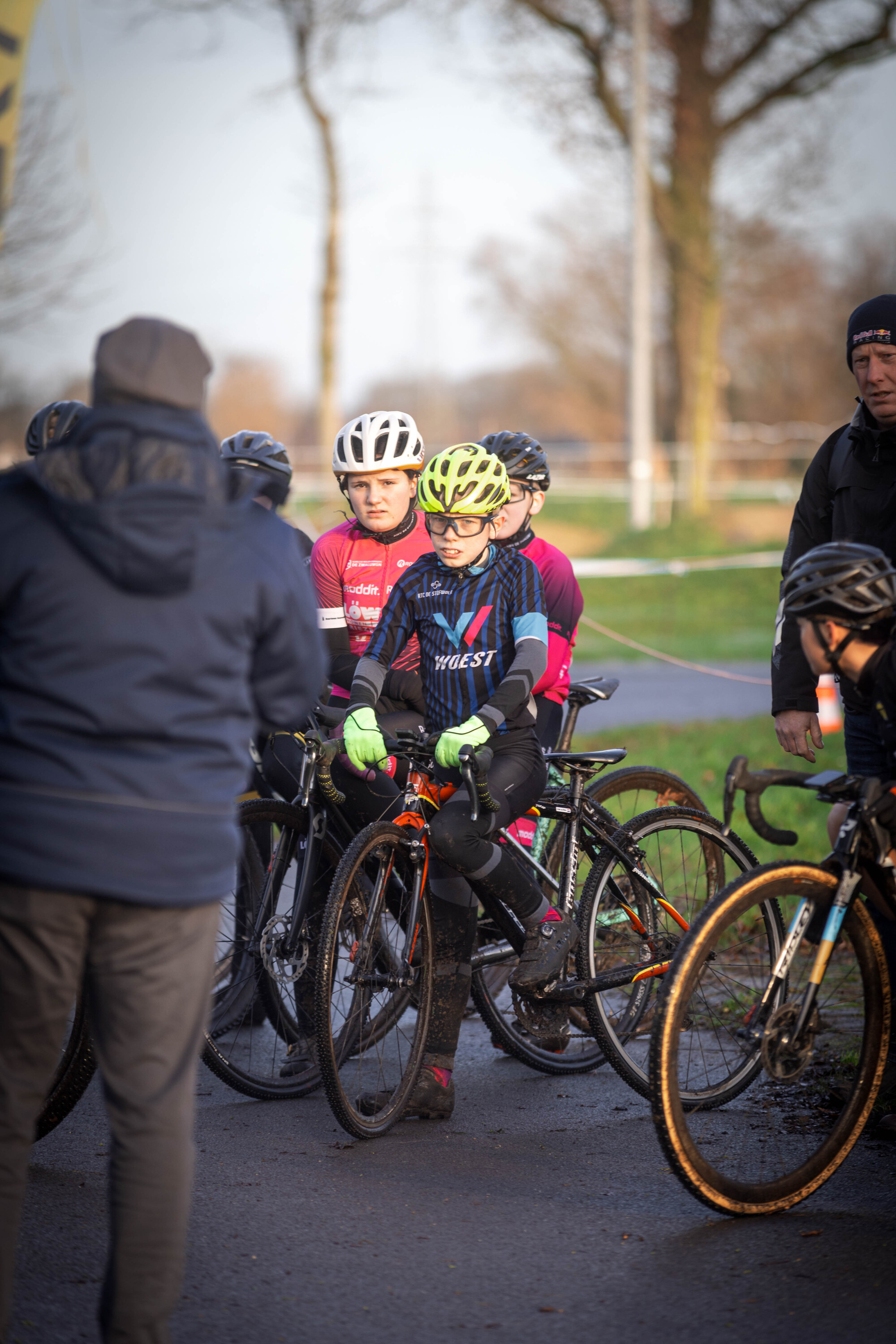 A group of young cyclists wearing helmets and riding bikes with one wearing a shirt saying GOW.