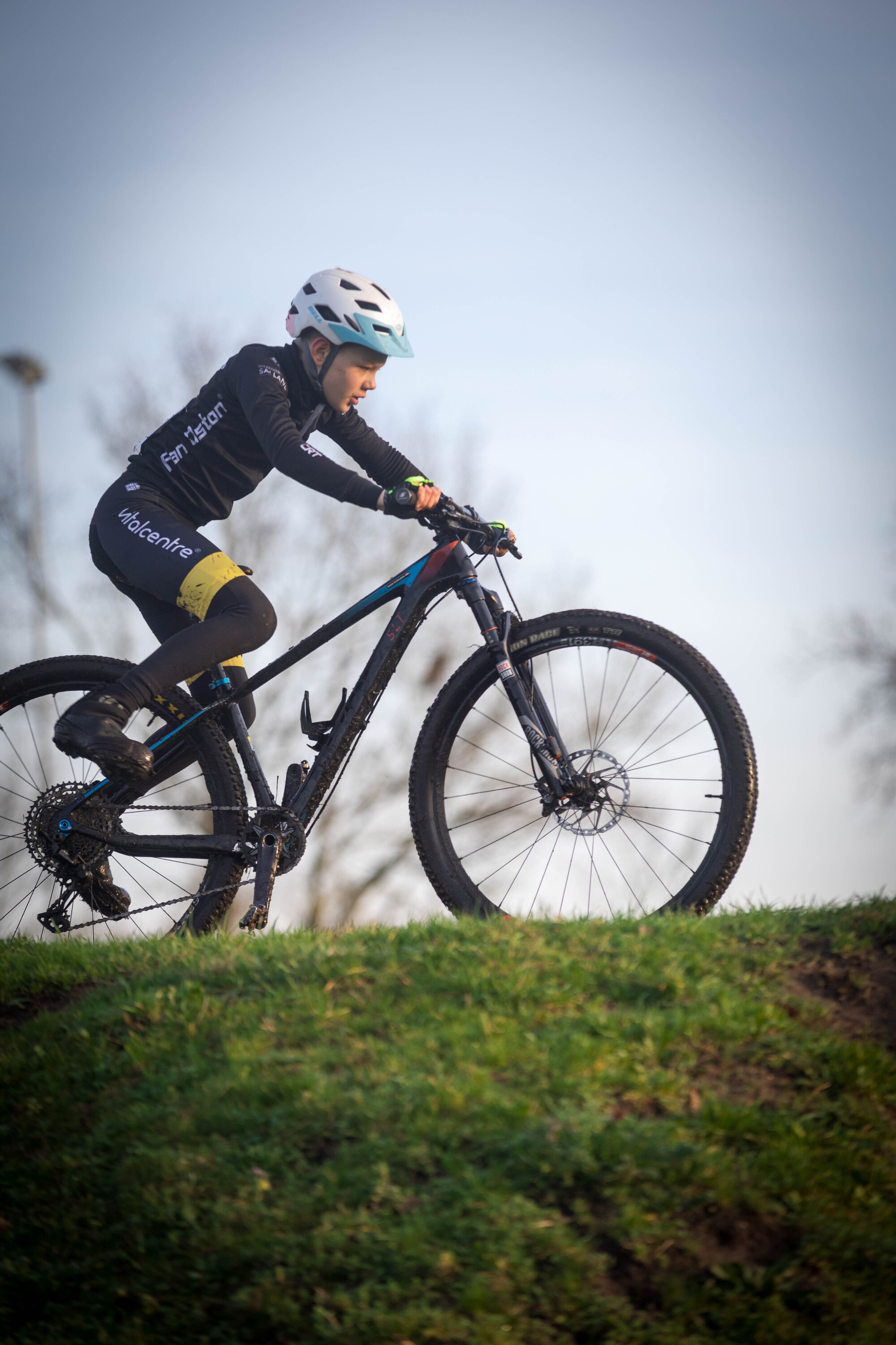 A person wearing a blue helmet riding a mountain bike on grass.