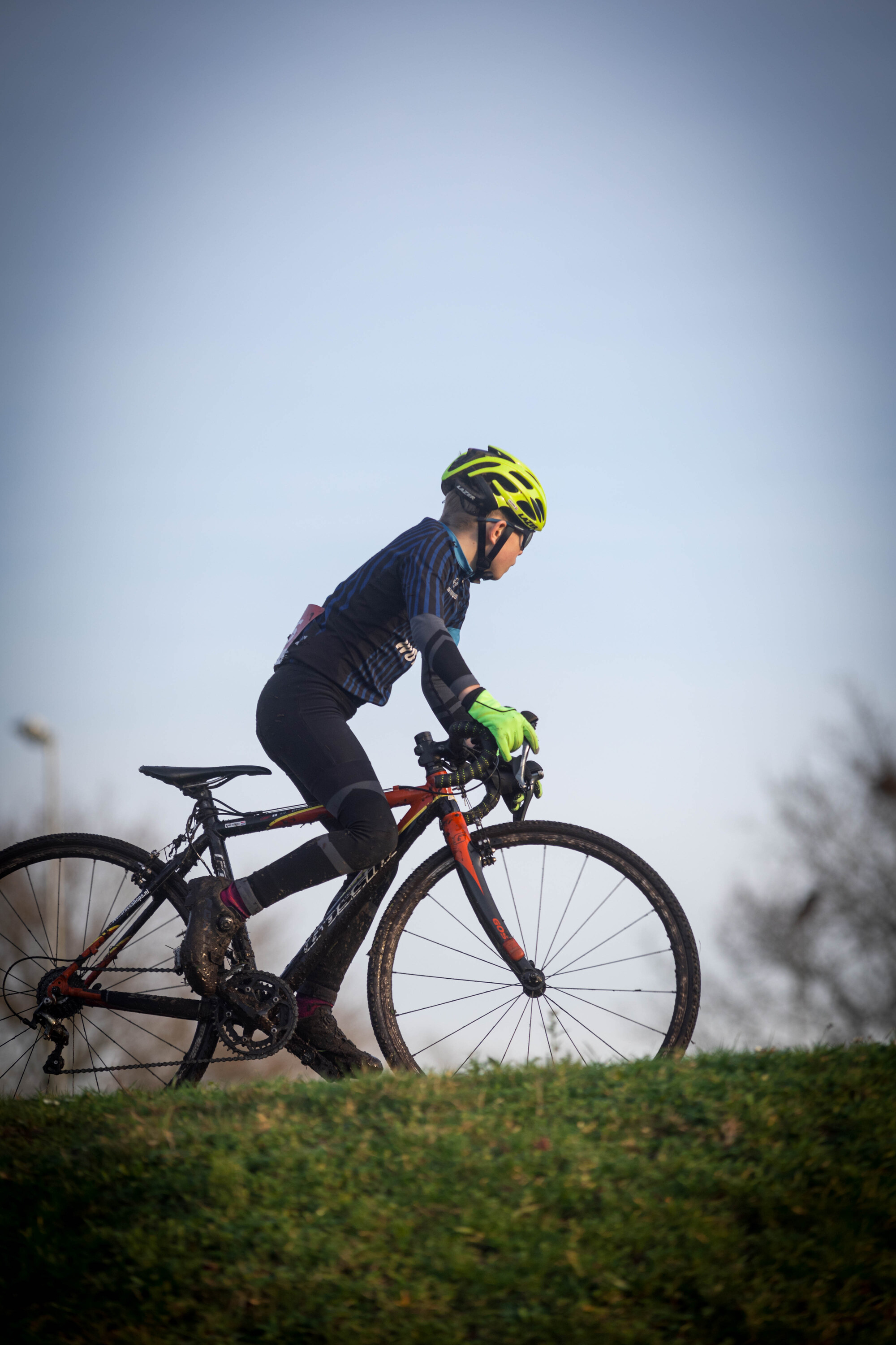 A person riding a bicycle while wearing a yellow helmet.