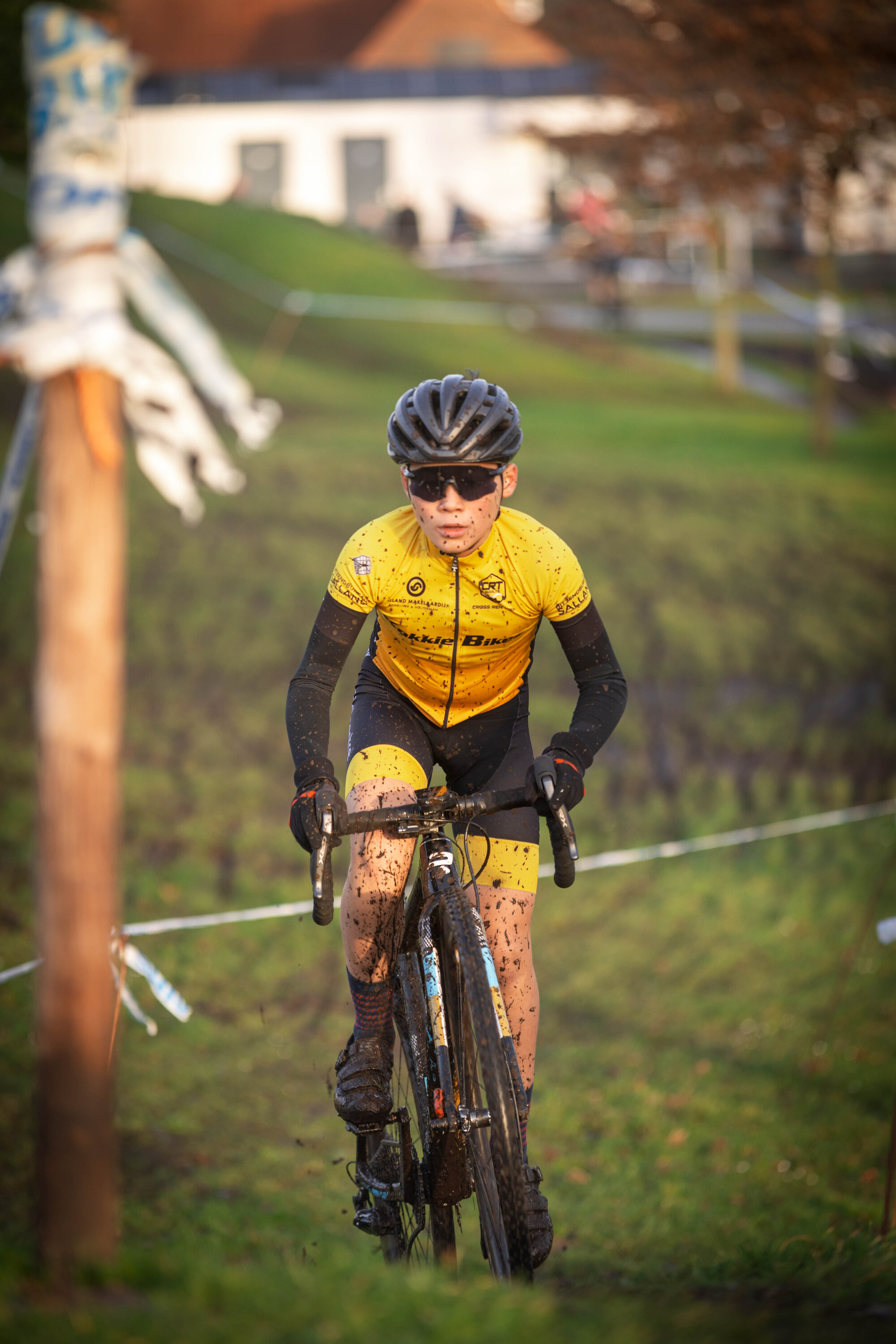 A young cyclist with a yellow and black jersey on is riding his bicycle.