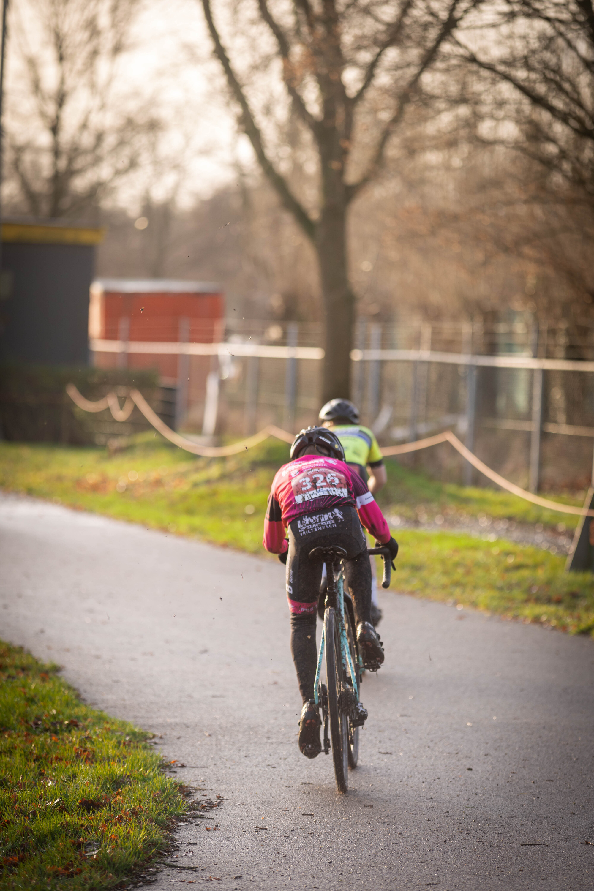 Two kids on bikes, with one wearing a shirt that says Jeug on the back.