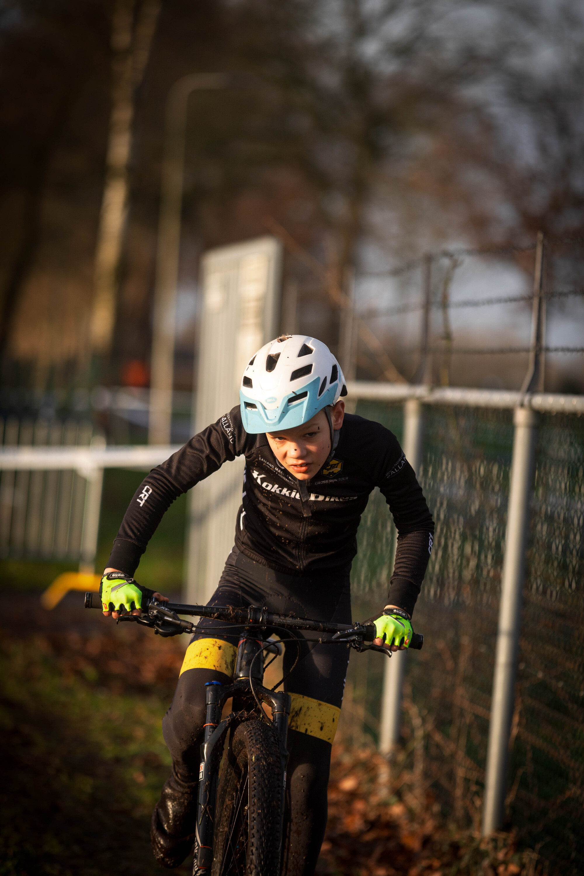 A young boy riding a bicycle with the word Jeug printed on it.