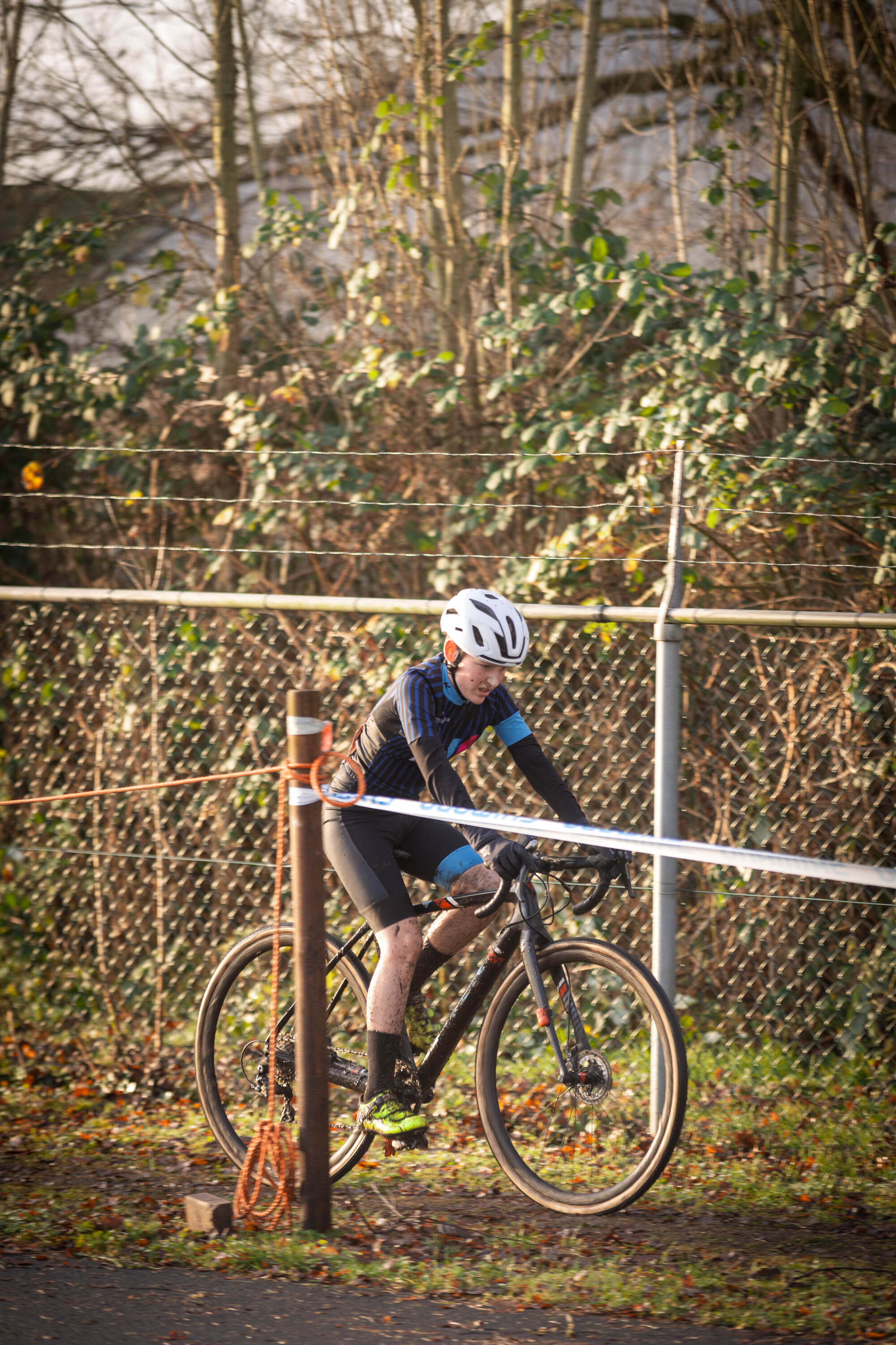 Cyclist wearing white helmet on a bicycle next to a orange pole.