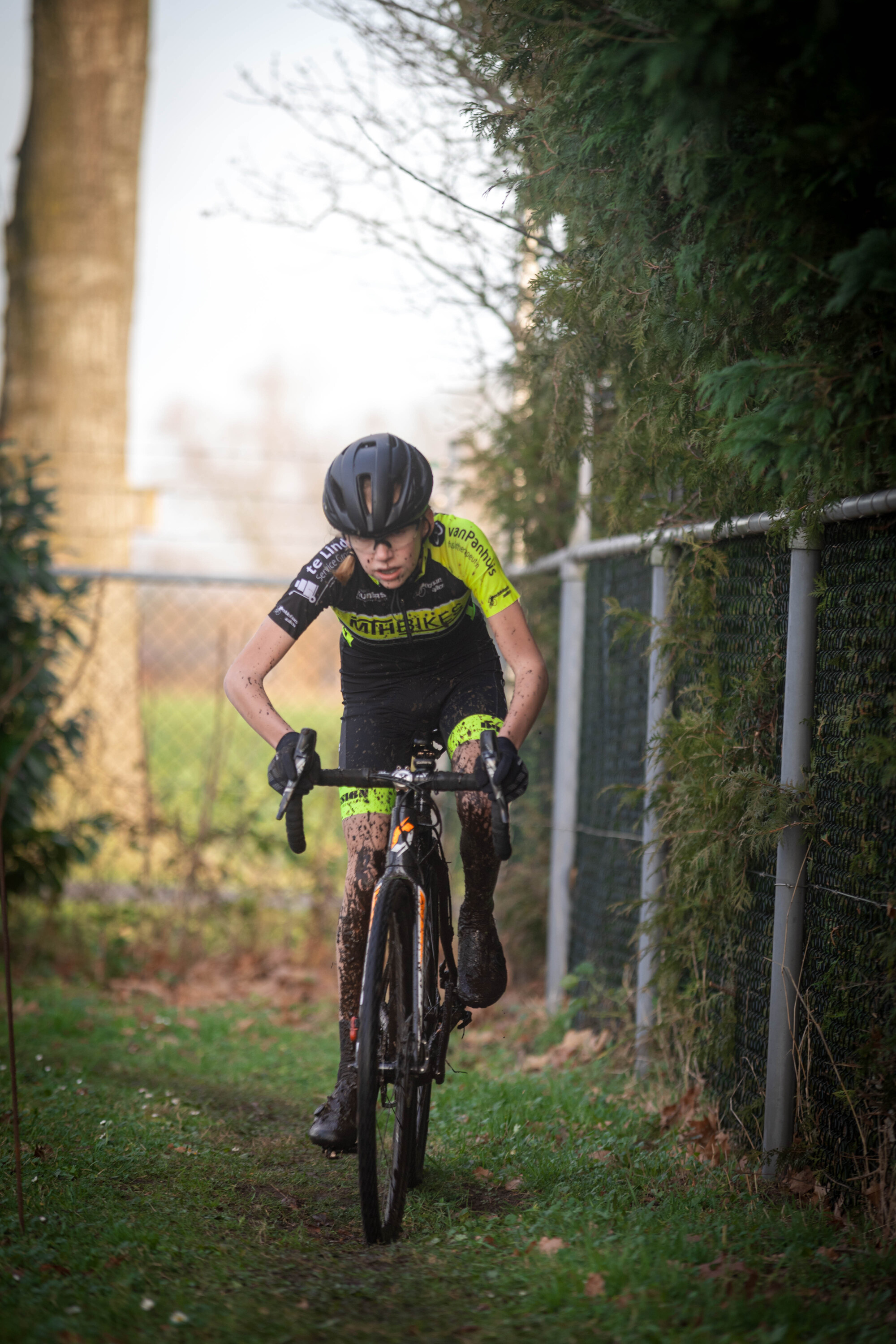 A person wearing a yellow and black shirt riding a bicycle.