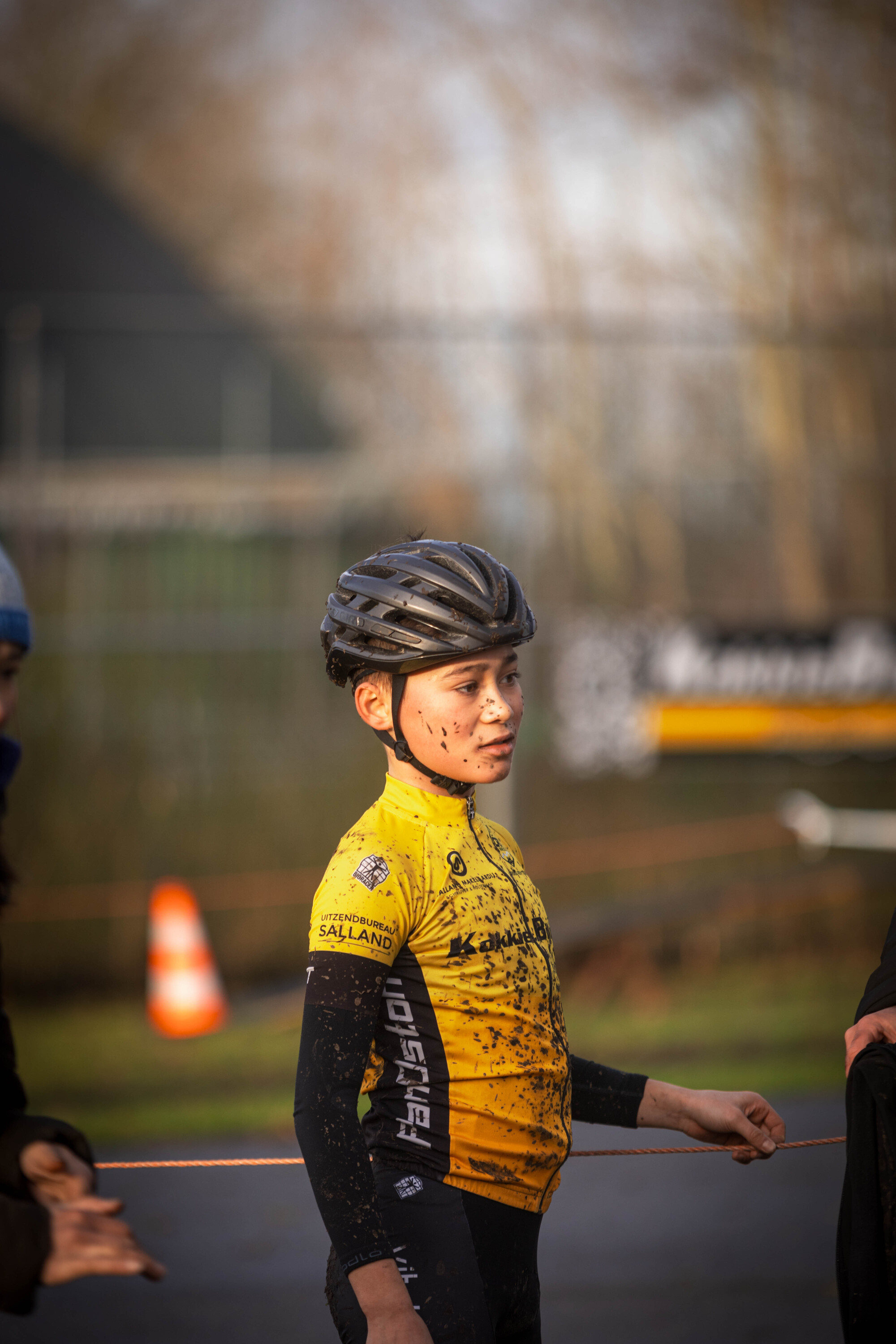 A young girl is wearing a yellow shirt and standing next to another person.