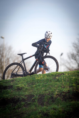 A person wearing a helmet stands in the background with their bicycle.