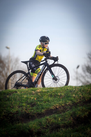 A person wearing a yellow and black shirt riding a bike on the grass.