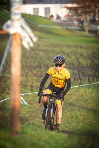 A boy wearing a yellow shirt and black helmet is riding a bike.