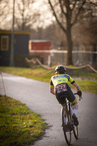 A person in a yellow and black shirt riding on a bicycle with the number 27.