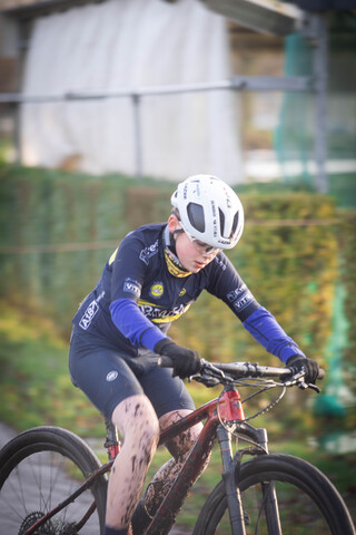 A young man riding a bicycle wearing a blue and black uniform.