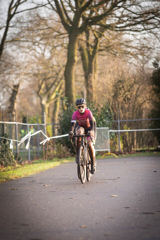 A young girl wearing a pink shirt is riding a bike on a road.