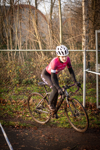 A woman in a pink shirt and black pants is riding her bike.