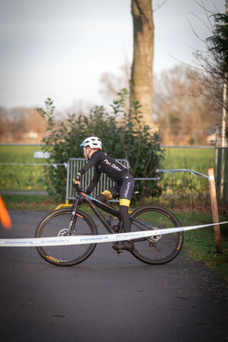 A man wearing a number 3 jersey rides his bicycle on the road.