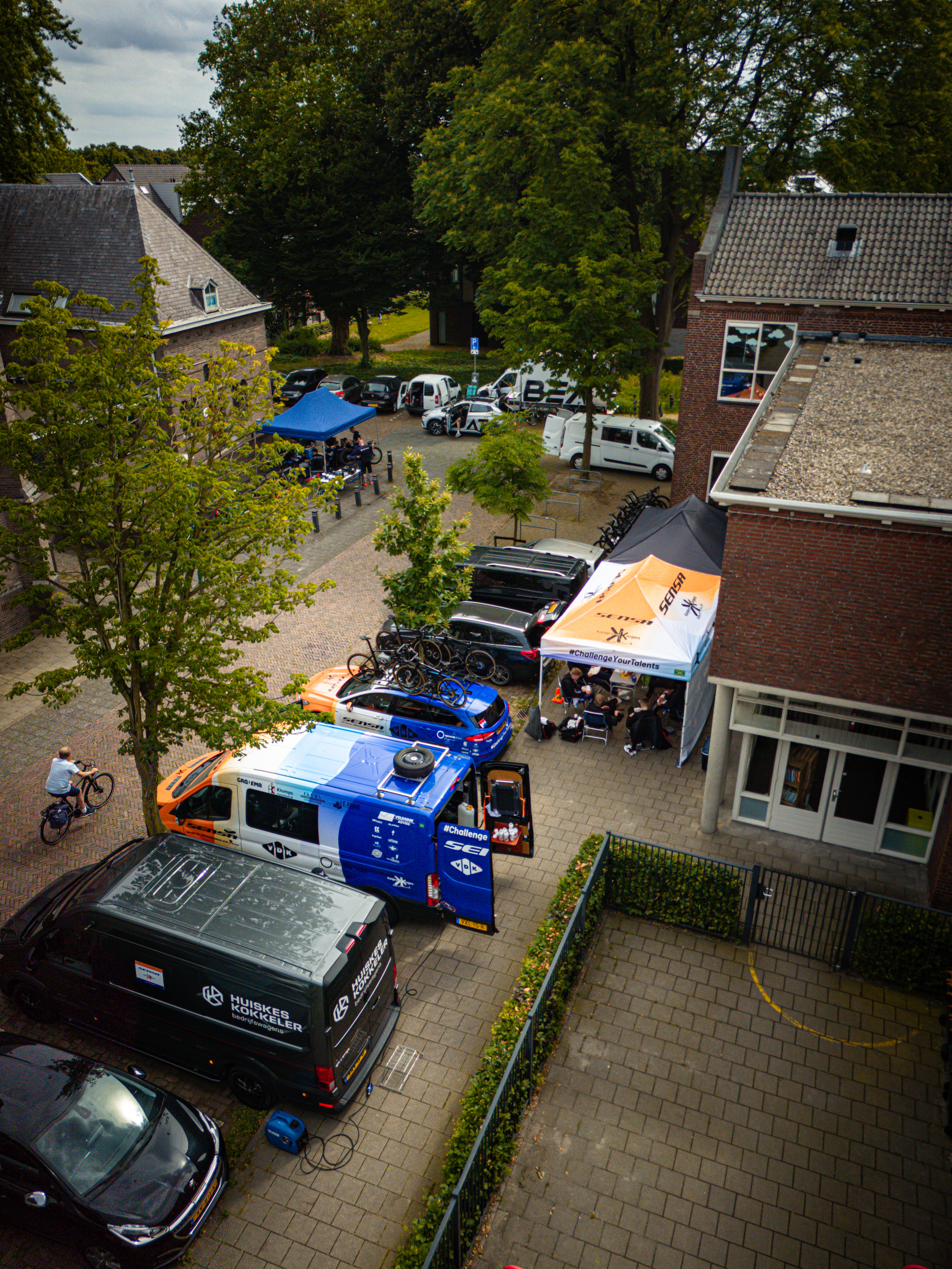 A group of cars on a street with a blue one and a van.