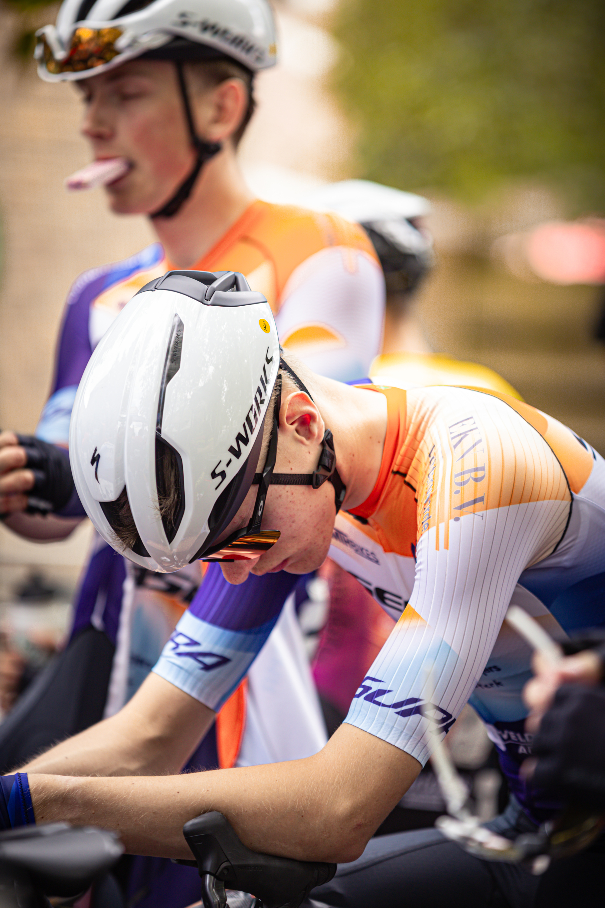 A cyclist wearing a shirt that says "Wielrennen" and "Midden Brabant Poort Omloop" rides his bike.