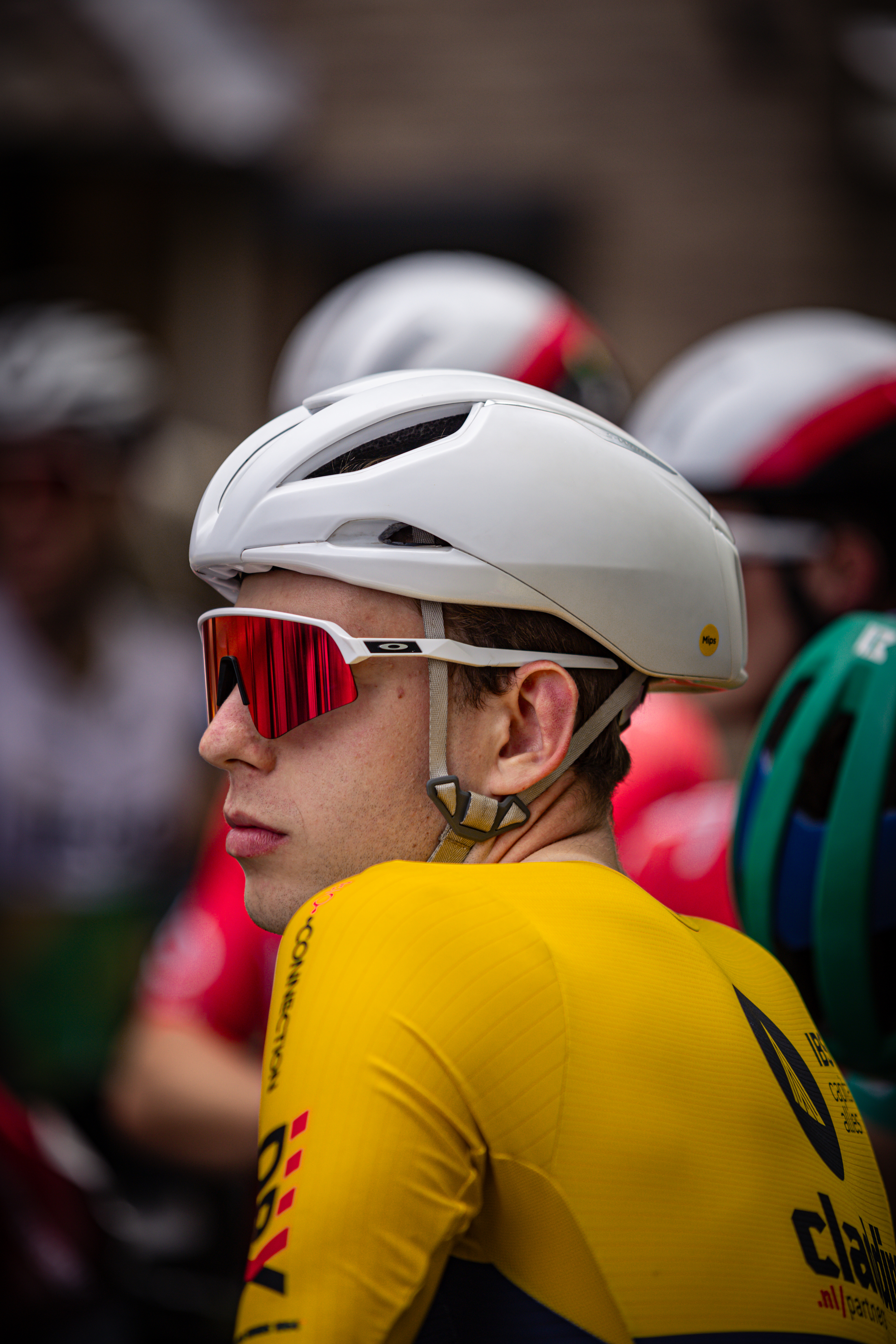 A cyclist is wearing a red and white helmet and glasses as he waits for his turn to race.