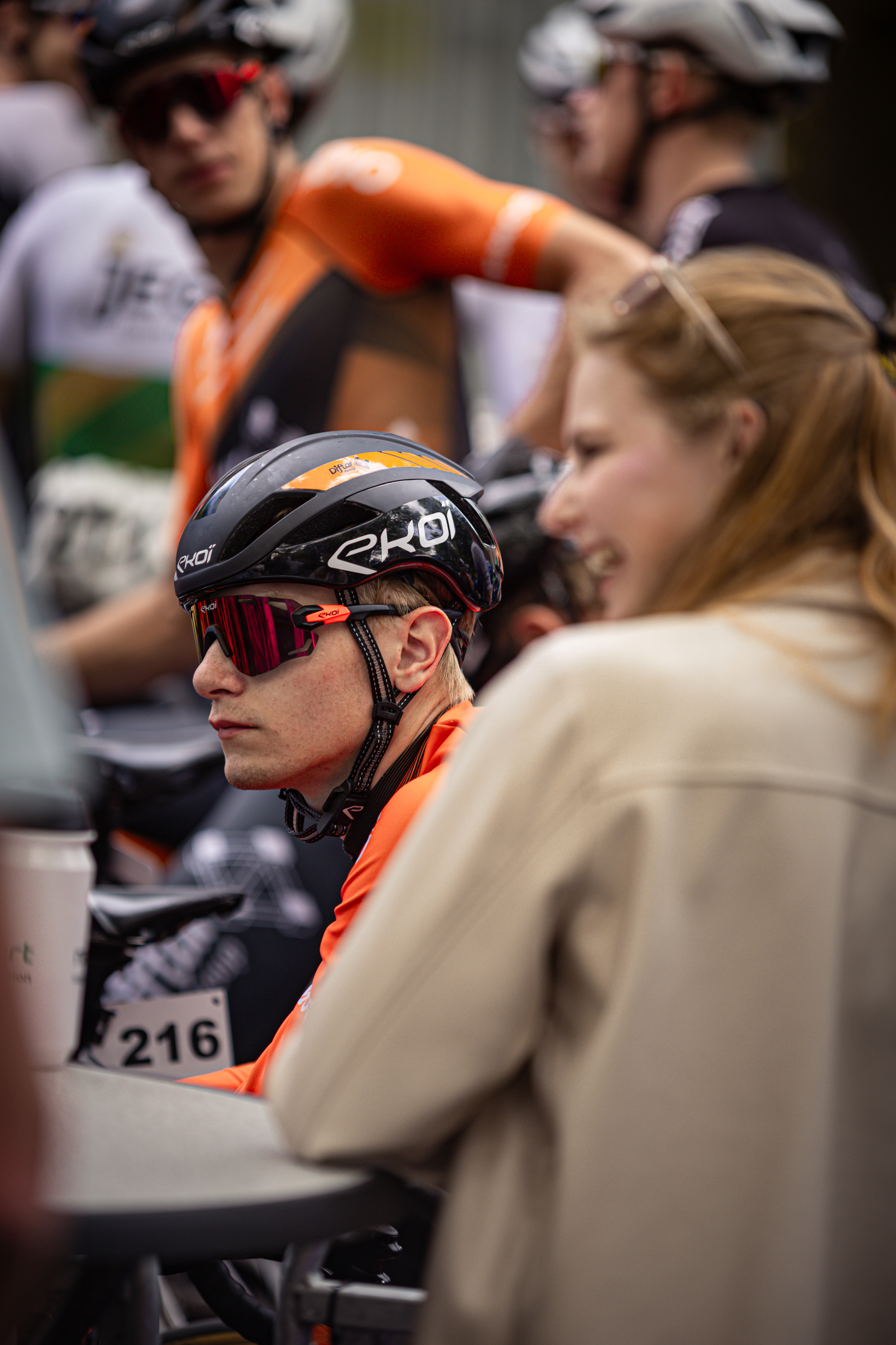 A cyclist wearing a black helmet with the number 21 on it sits looking to the side.