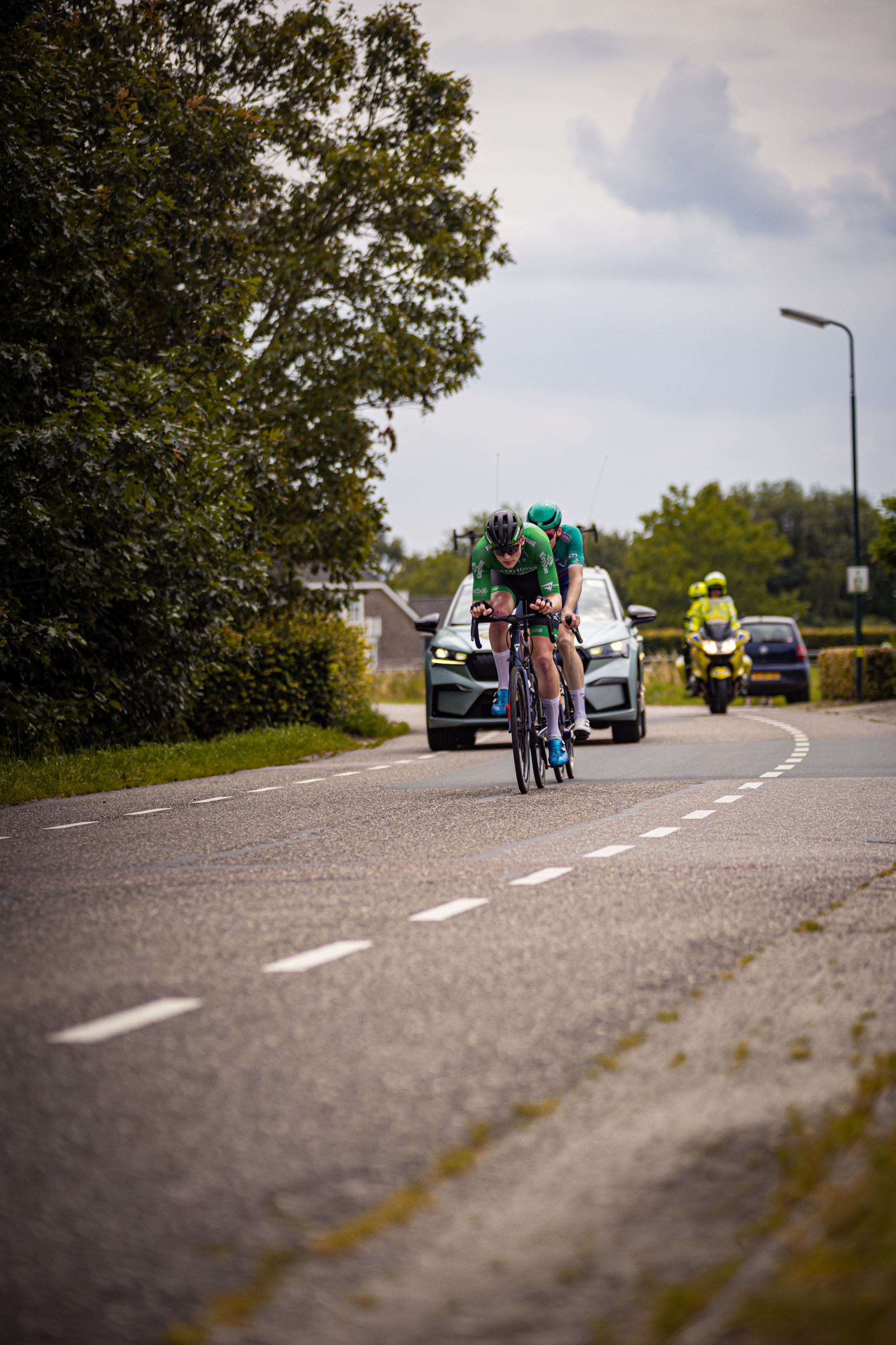 A man on a bike is riding down a street in the Netherlands during a cycling race.