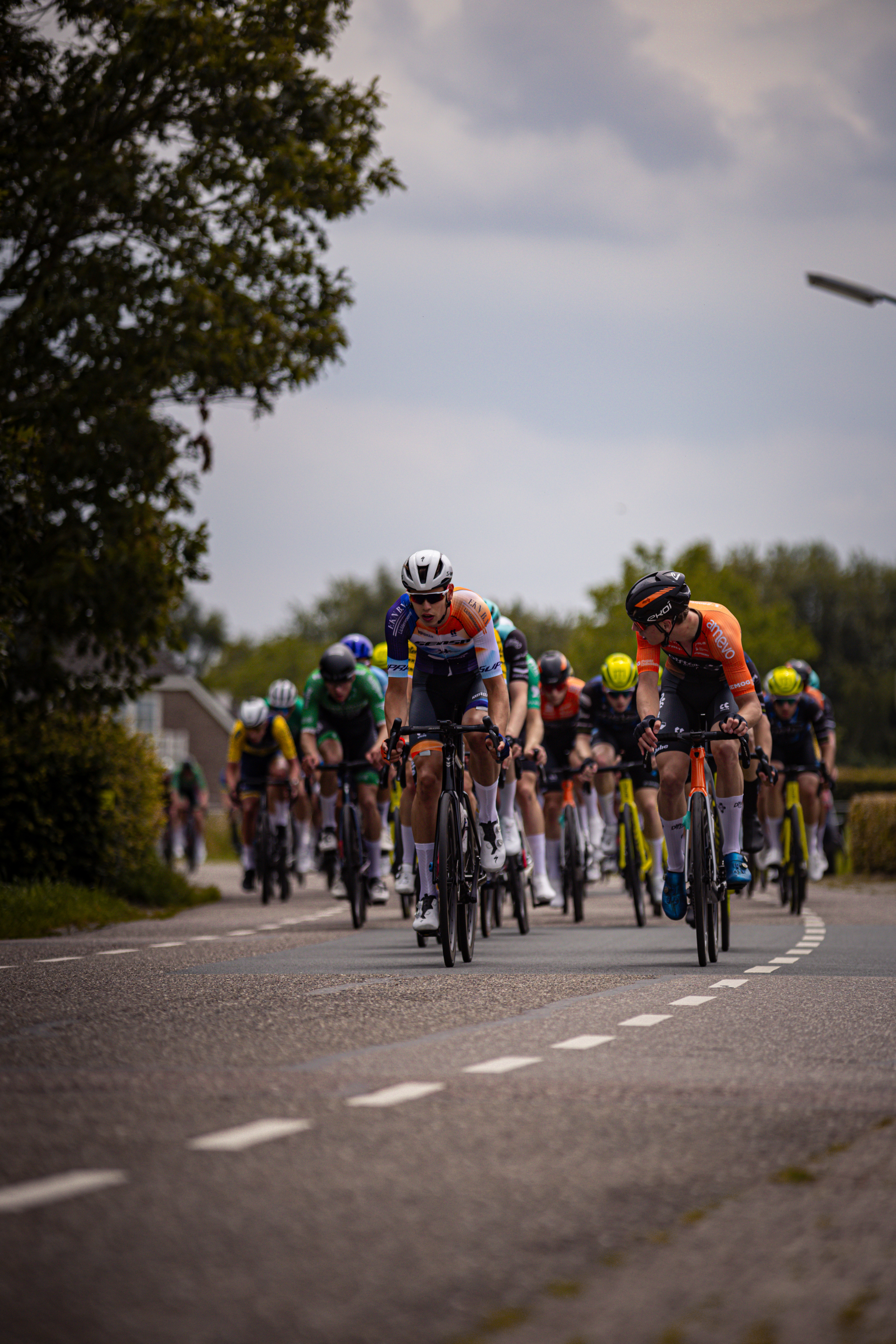 A group of cyclists race down a road during the Midden Brabant Poort Omloop event.