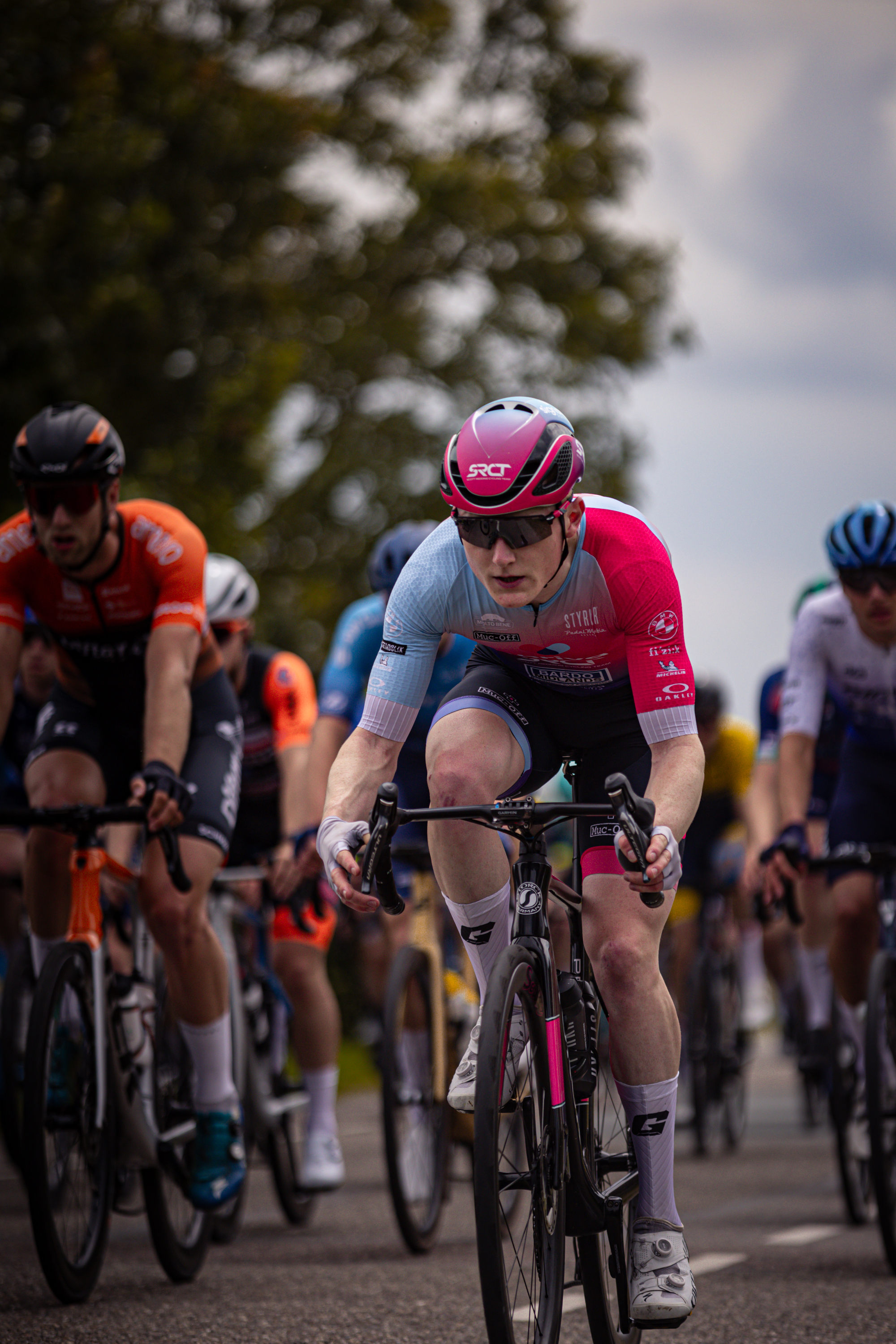 A cyclist is wearing a blue and white jersey with the word "Wielrennen" on it.