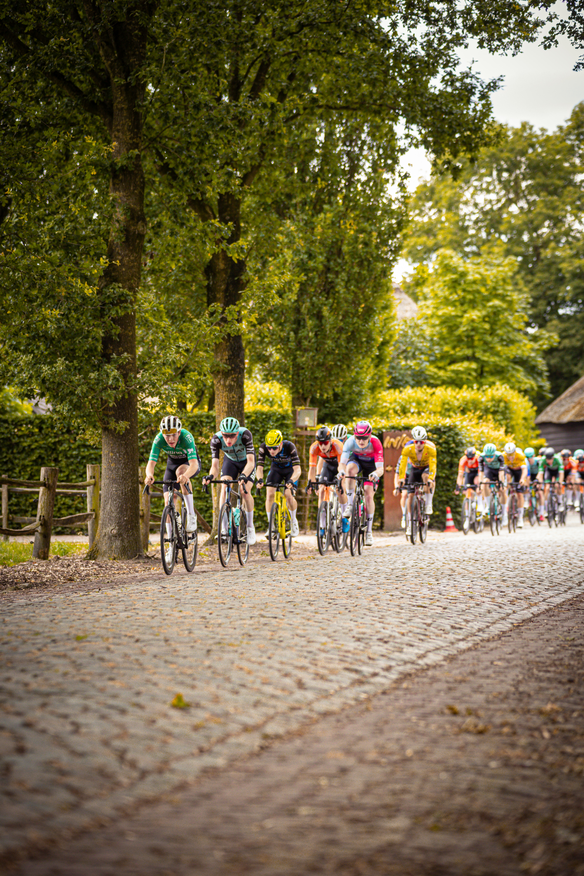 A group of cyclists ride down a cobblestone road in the Netherlands.