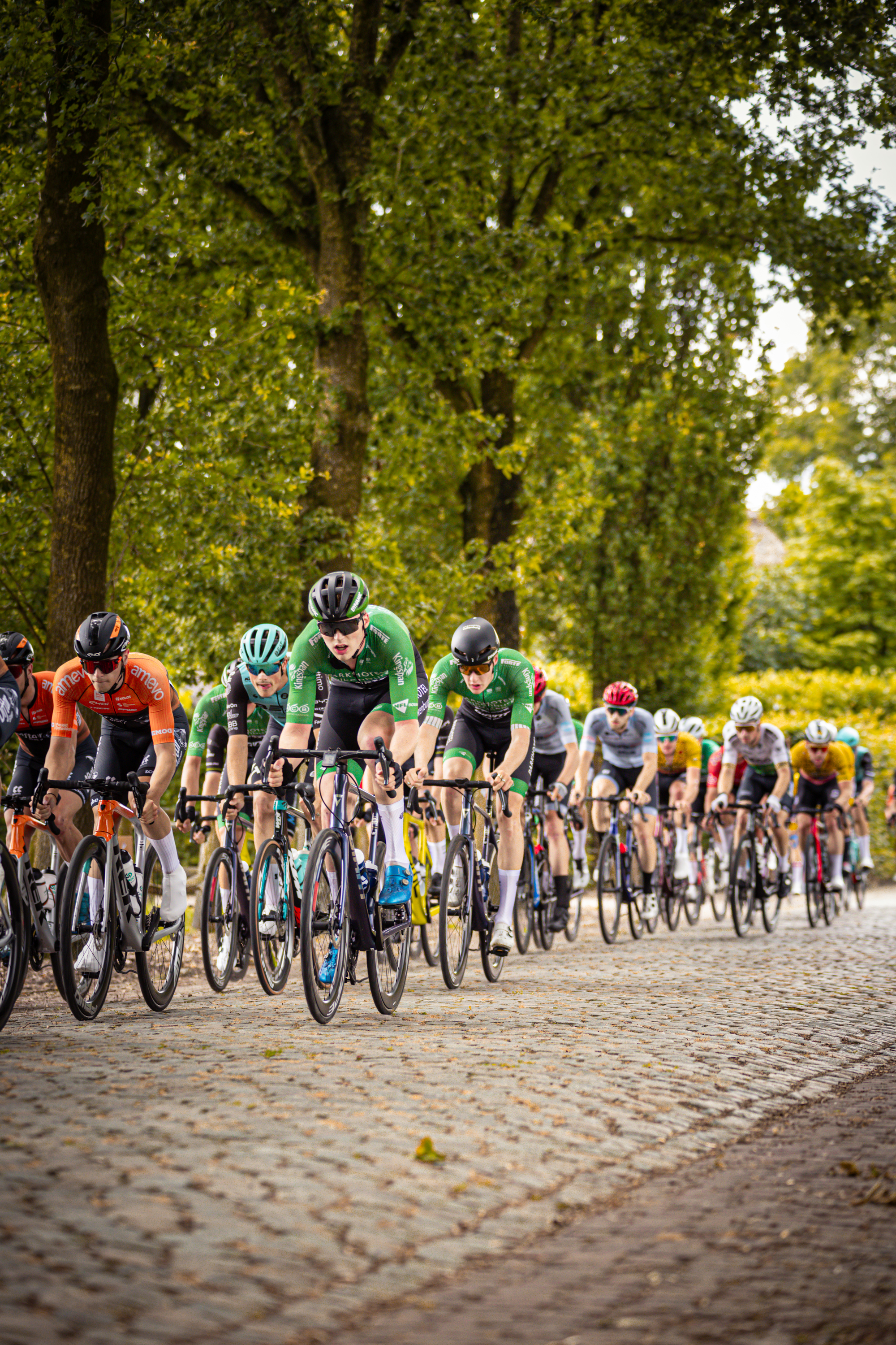 The cyclists in the image are participating in the Midden Brabant Poort Omloop, a cycling event held in 2024.