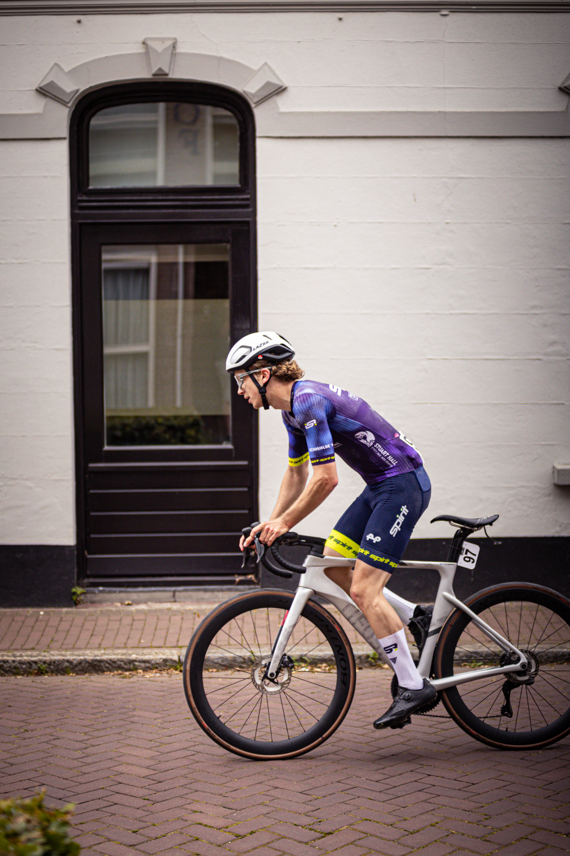 A person in a blue and purple jersey is riding a bike.