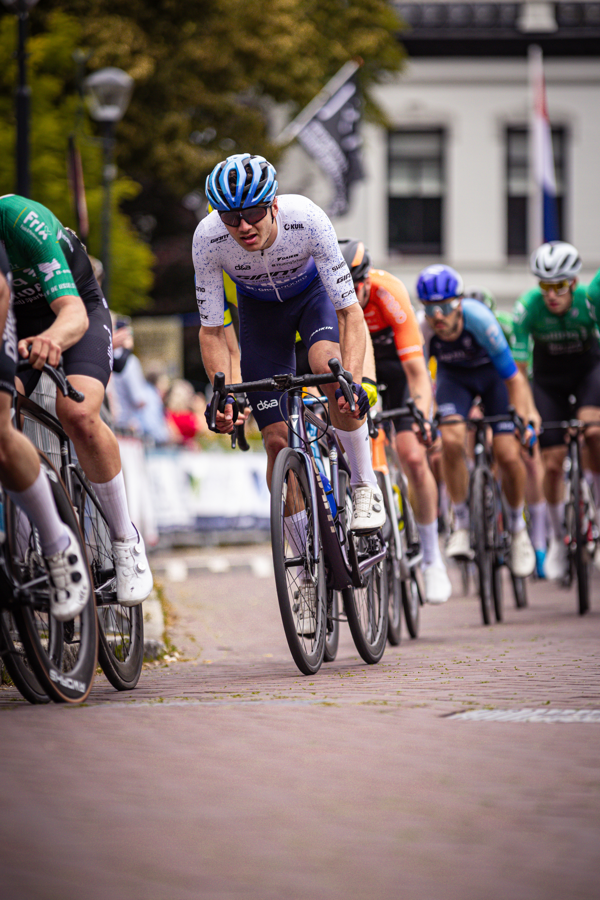 A man wearing a blue helmet is riding a bike at the Midden Brabant Poort Omloop.