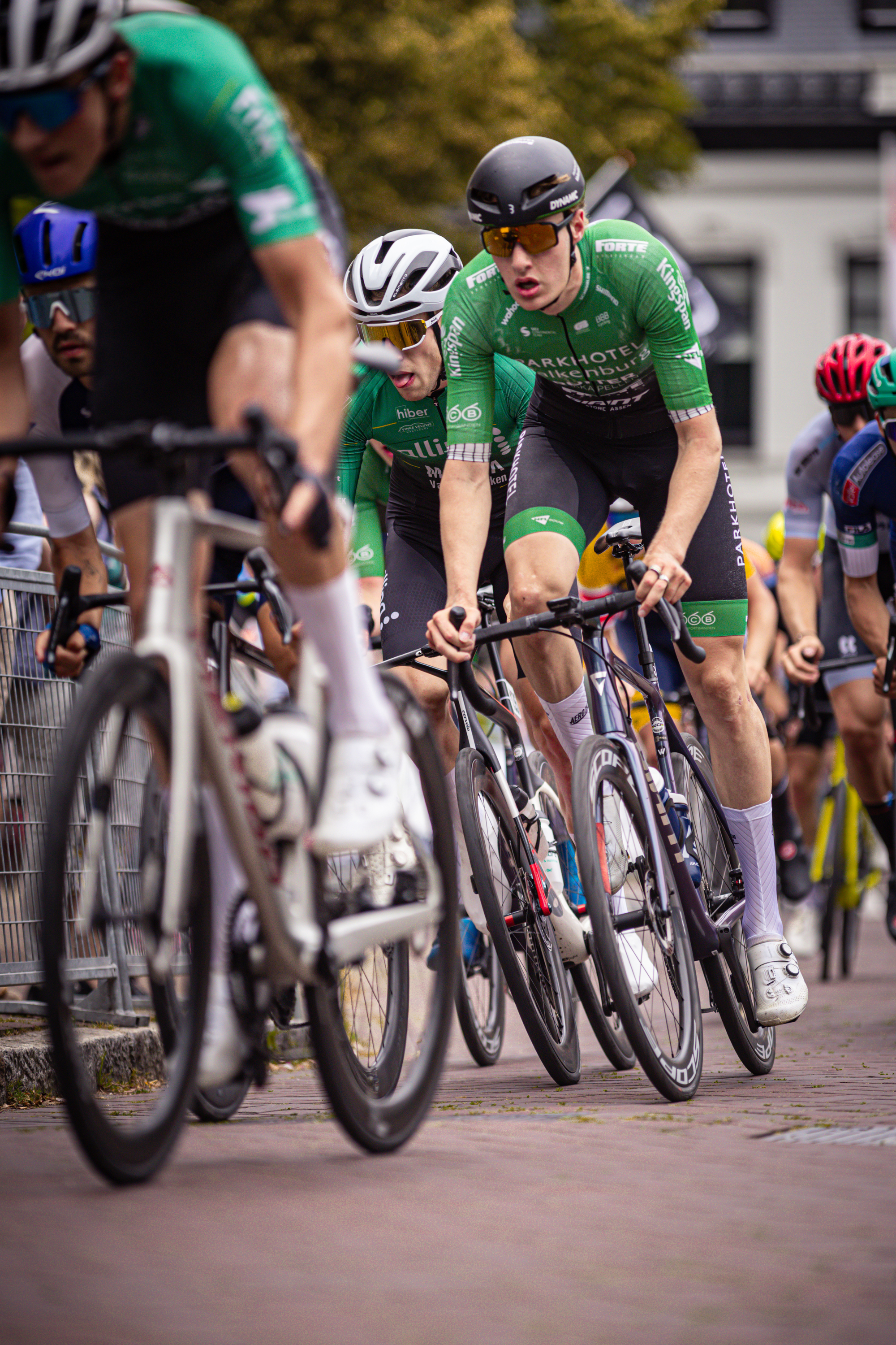 A cyclist on a road with other cyclists, participating in the Midden Brabant Poort Omloop event.