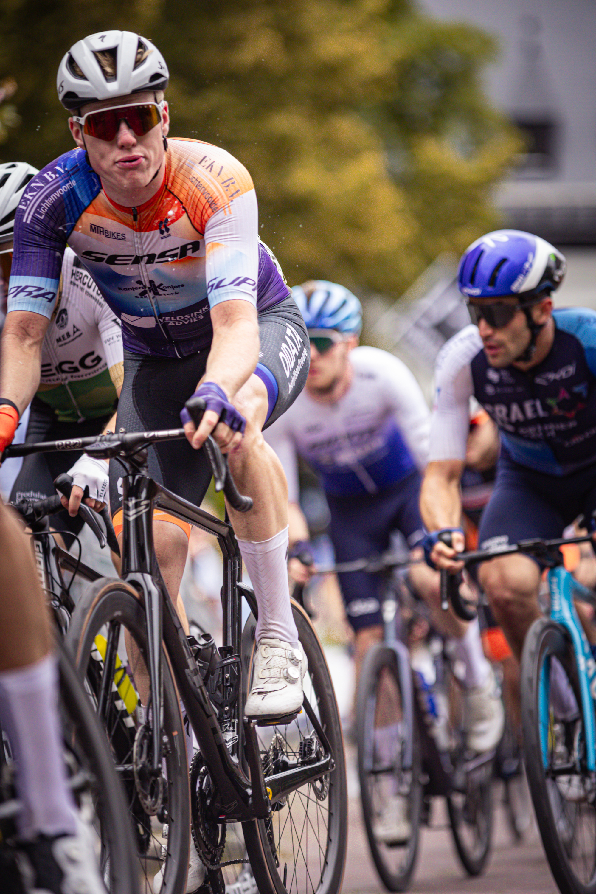 A group of men race on bikes in a Midden Brabant Poort Omloop.