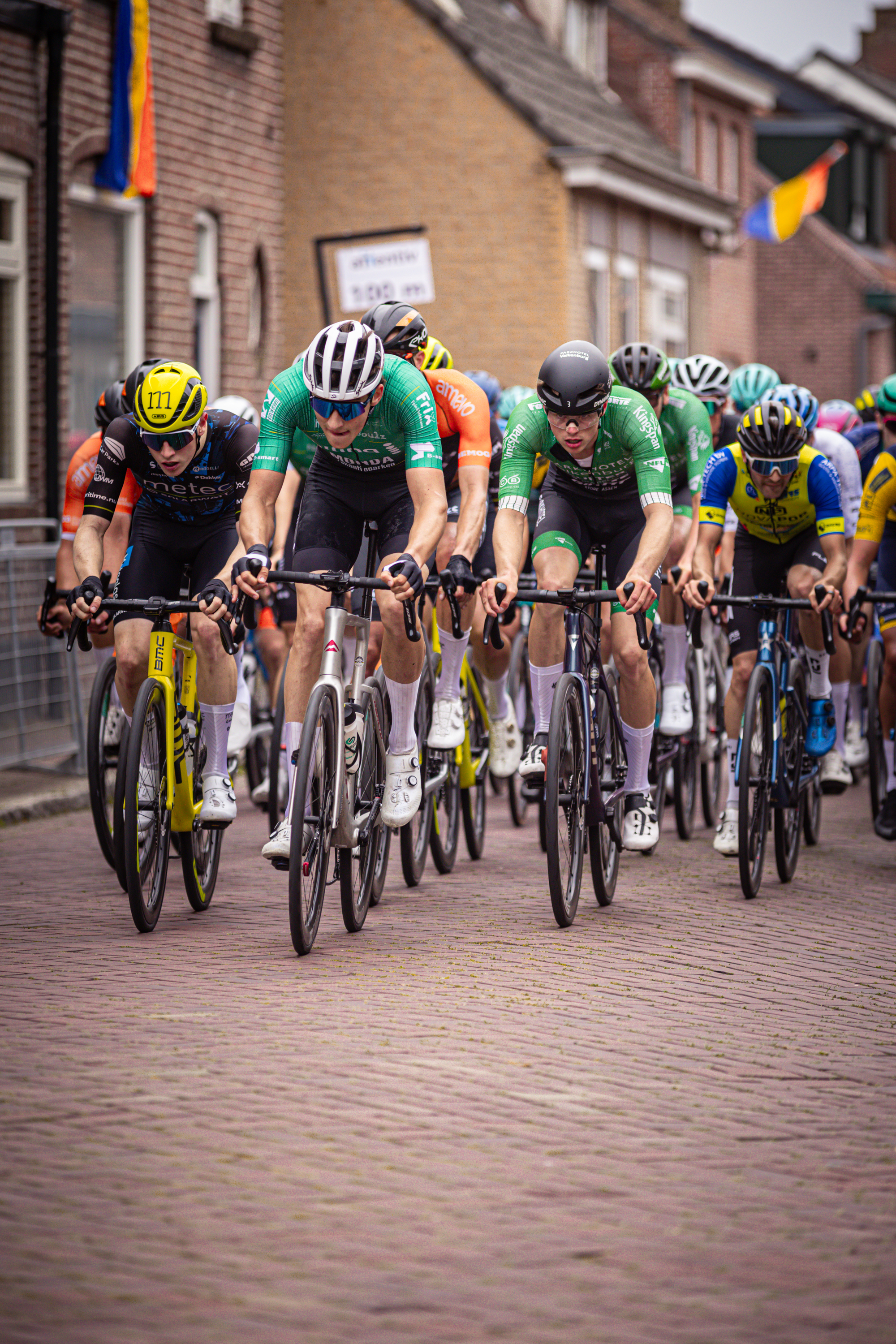 Group of cyclists on a street in Midden Brabant, participating in the Omloop race.