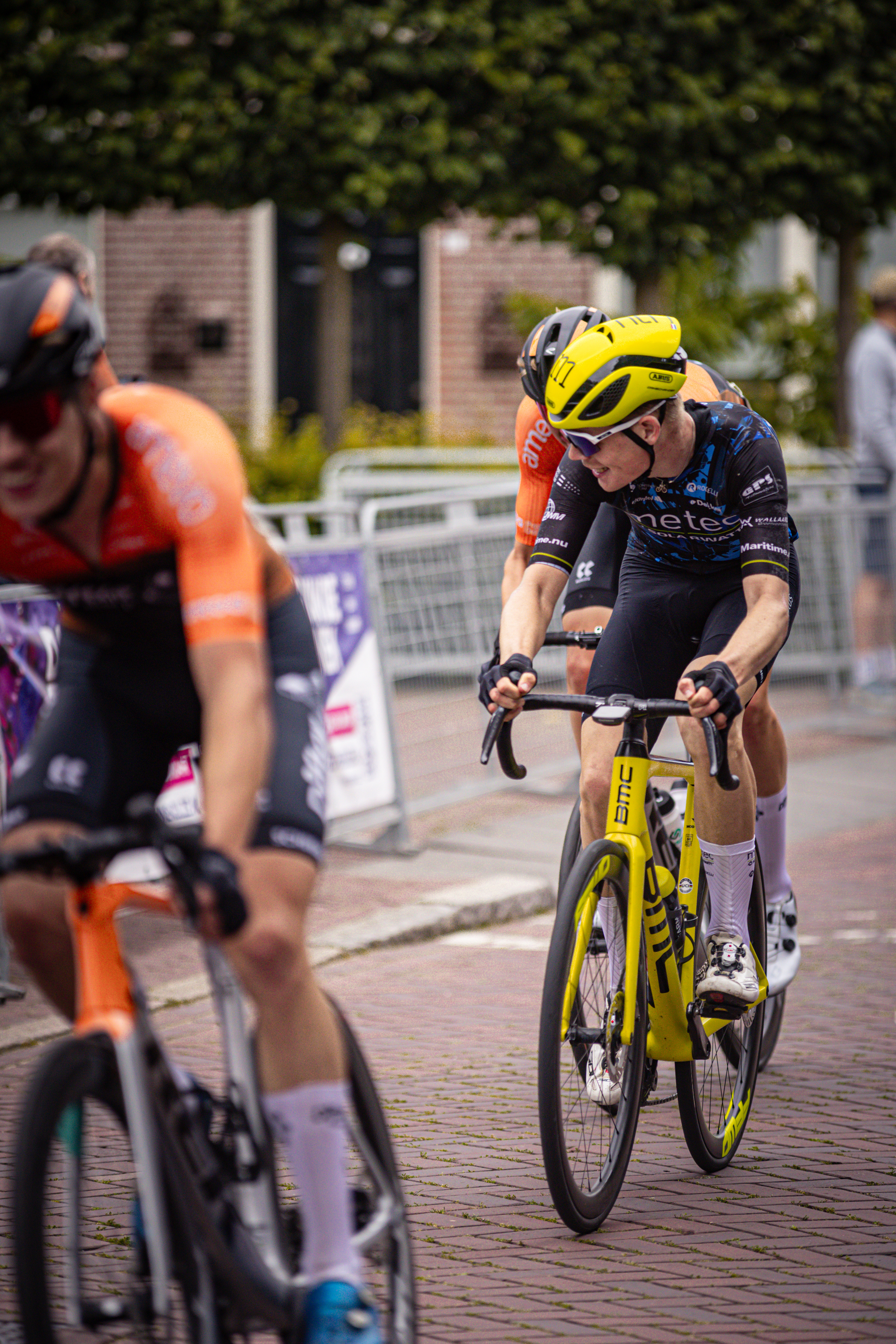 A group of cyclists are riding on a street in the Midden Brabant Poort Omloop race.