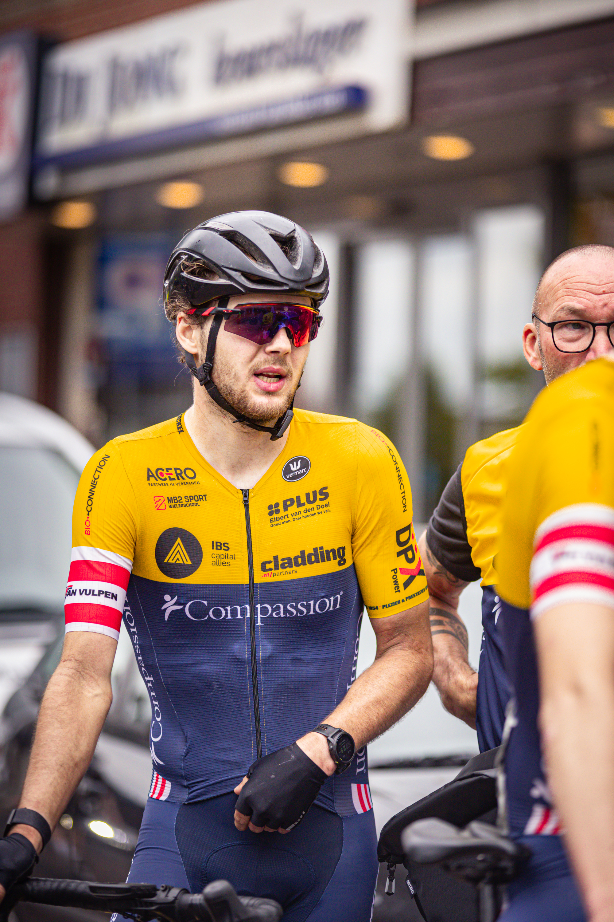 Two cyclists on a street in front of a building with the name "Dr. Dong" above them.