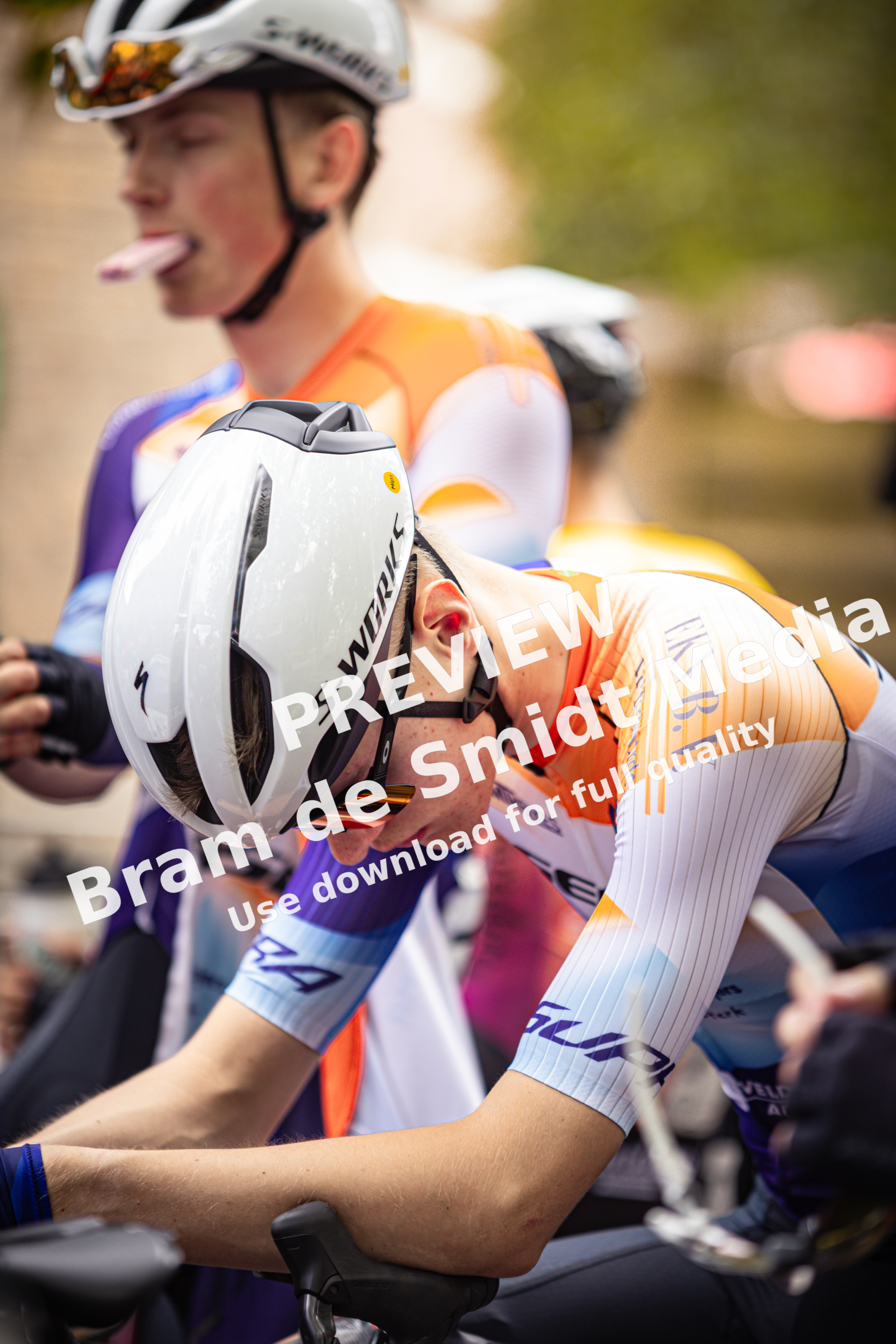 A cyclist wearing a shirt that says "Wielrennen" and "Midden Brabant Poort Omloop" rides his bike.