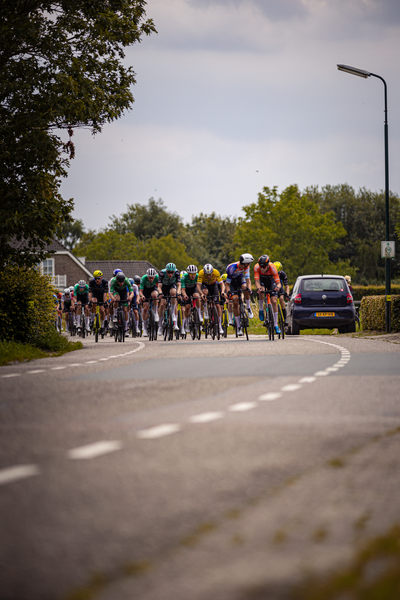 A group of cyclists in the Midden Brabant Poort Omloop race are coming down a road.