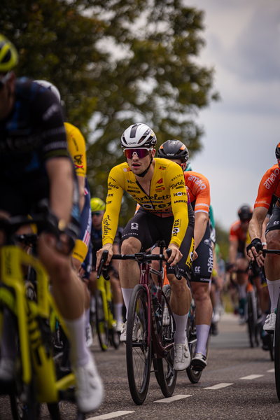 Bicyclist wearing yellow and black outfit riding bike.