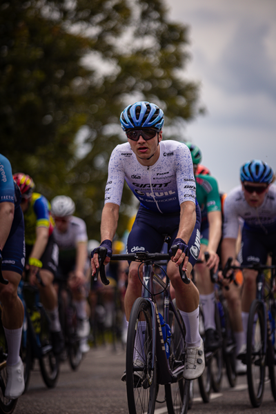 A group of cyclists riding down a street in the Midden Brabant Poort Omloop.