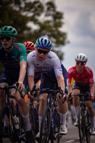 A group of cyclists in a race with the number 15 on their helmets are all wearing bibs.