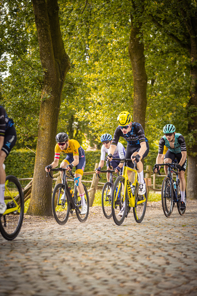 Three cyclists are riding on a cobblestone path in Midden Brabant.