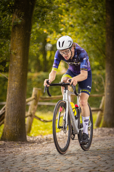 A cyclist on a cobblestone road with the number 21 on his helmet.