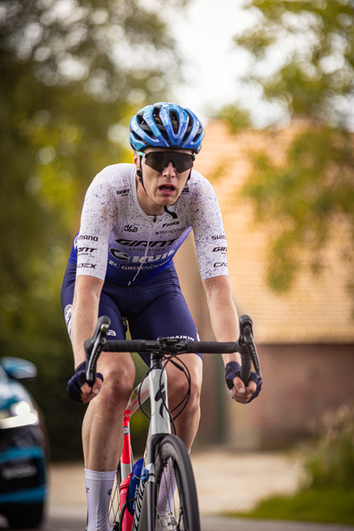 A person in a blue helmet and matching outfit riding a bike.