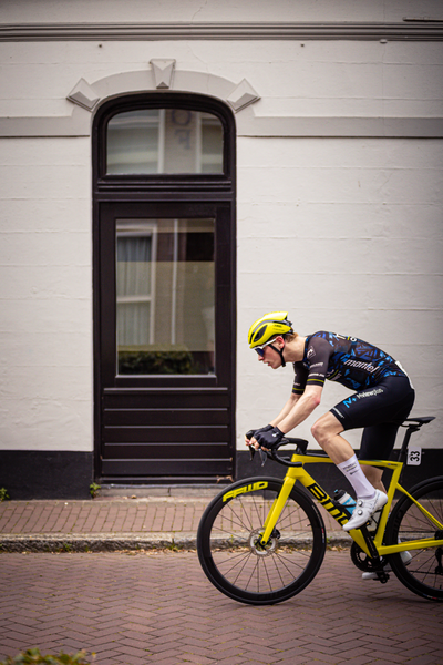 A man wearing a black and blue jersey rides on a yellow bicycle.