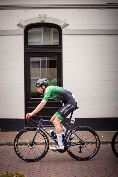 A cyclist dressed in a green and black jersey with the number 22 on it.