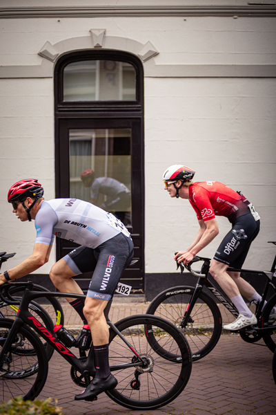 A group of cyclists riding down a road, one wearing black and the other red.