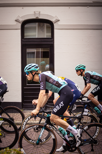 A group of cyclists in blue and white jerseys are racing on a track.