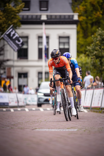 Two cyclists are riding a road in the Midden Brabant Poort Omloop.