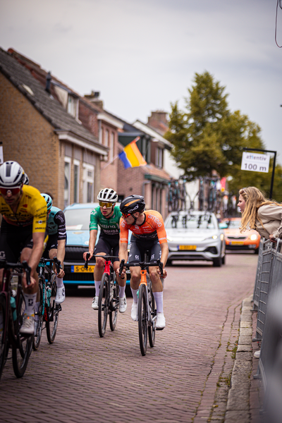 A group of cyclists are riding on a cobblestone road in the city of Midden Brabant during the 2024 Wielrennen event.