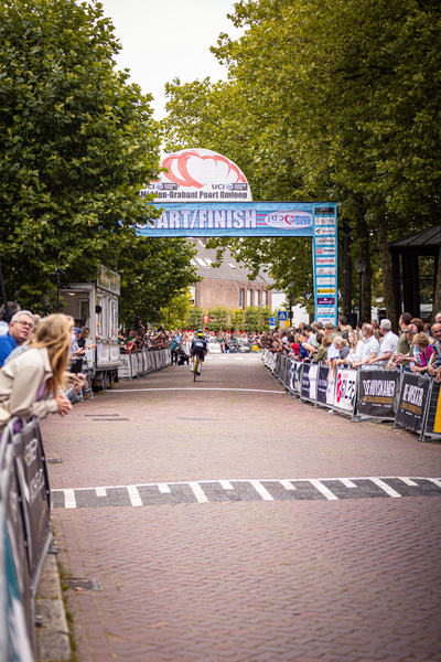 A picture of a crowd watching a cyclist on a track with the text "Wielrennen" above it.