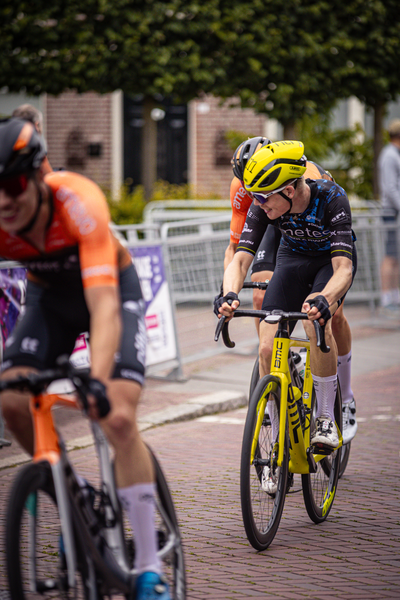 A group of cyclists are riding on a street in the Midden Brabant Poort Omloop race.