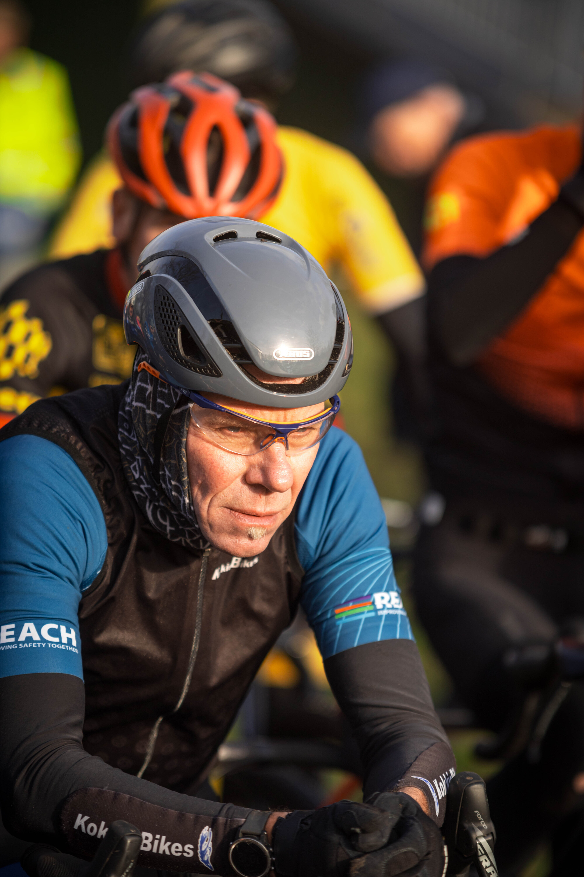 A man in a blue shirt and helmet with a bike behind him.